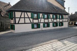 Façade à colombages rénovée d'une maison alsacienne, vue d'angle sur rue