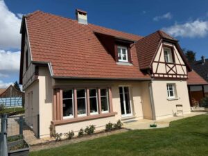 Façade rénovée d'une maison alsacienne à colombages avec véranda et lucarnes